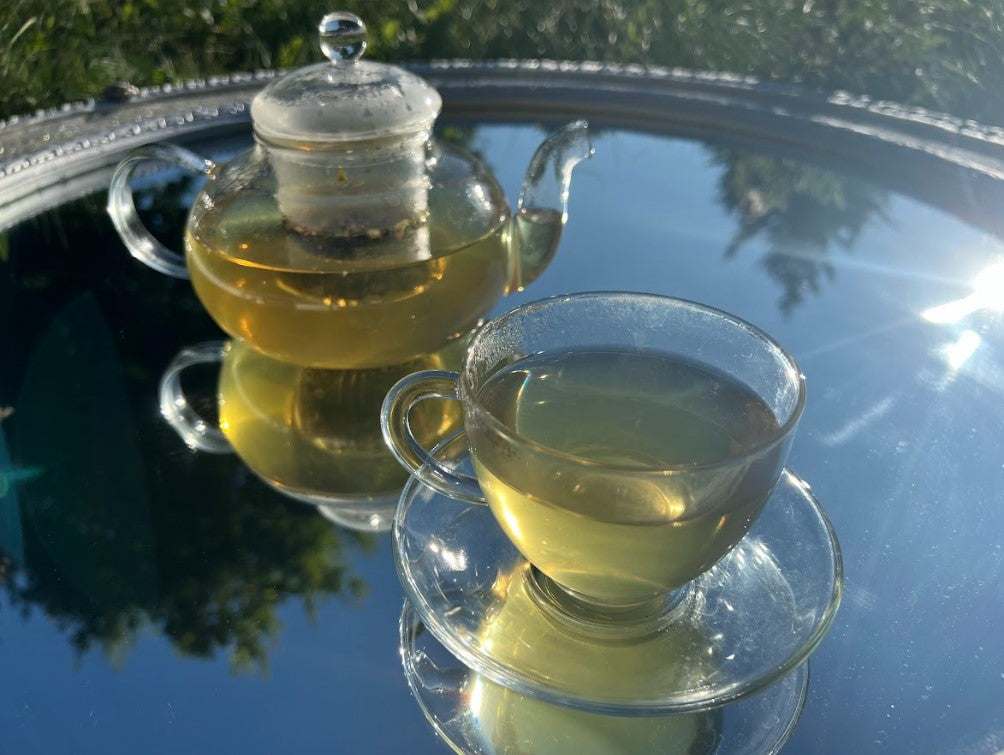 Sleep and Reset Calming Herbal Tea Blend Warm lifestyle photo of a glass teapot pouring golden herbal TEATOX tea into a clear cup, highlighting the cooling hue from the valerian root lemon balm herb mix