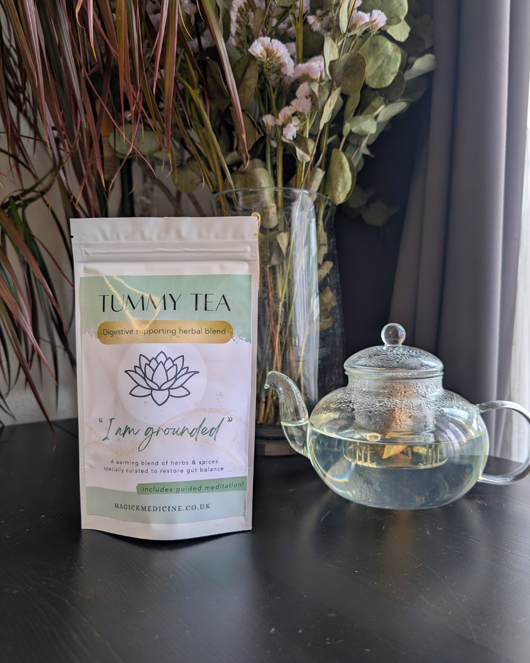 Tummy Tea pack beside a teapot, brewed and ready to pour